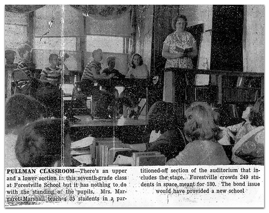 Black and white photograph of a newspaper clipping showing a classroom at the Forestville School. Students are seated at desks on the auditorium stage. A teacher is standing on the stage next to a bookshelf. The photograph caption reads: Pullman Classroom – There’s an upper and lower section in this seventh grade class at Forestville School but it has nothing to do with the standing of the pupils. Mrs. Margaret Marshall teaches 35 students in a partitioned-off section of the auditorium that includes the stage. Forestville crowds 249 students in a space meant for 180. The bond issue would have provided a new school.