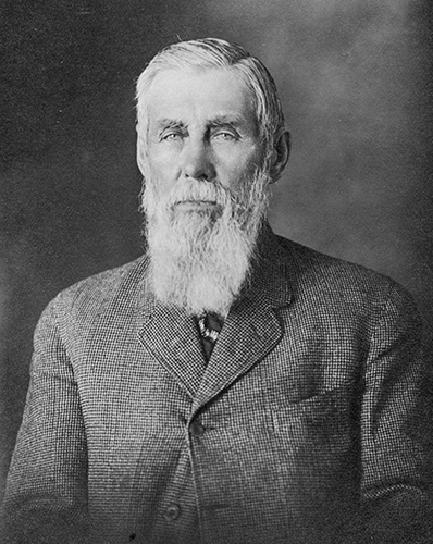Black and white, head-and-shoulders portrait of George Johnson. He is an older gentleman with a long white beard.