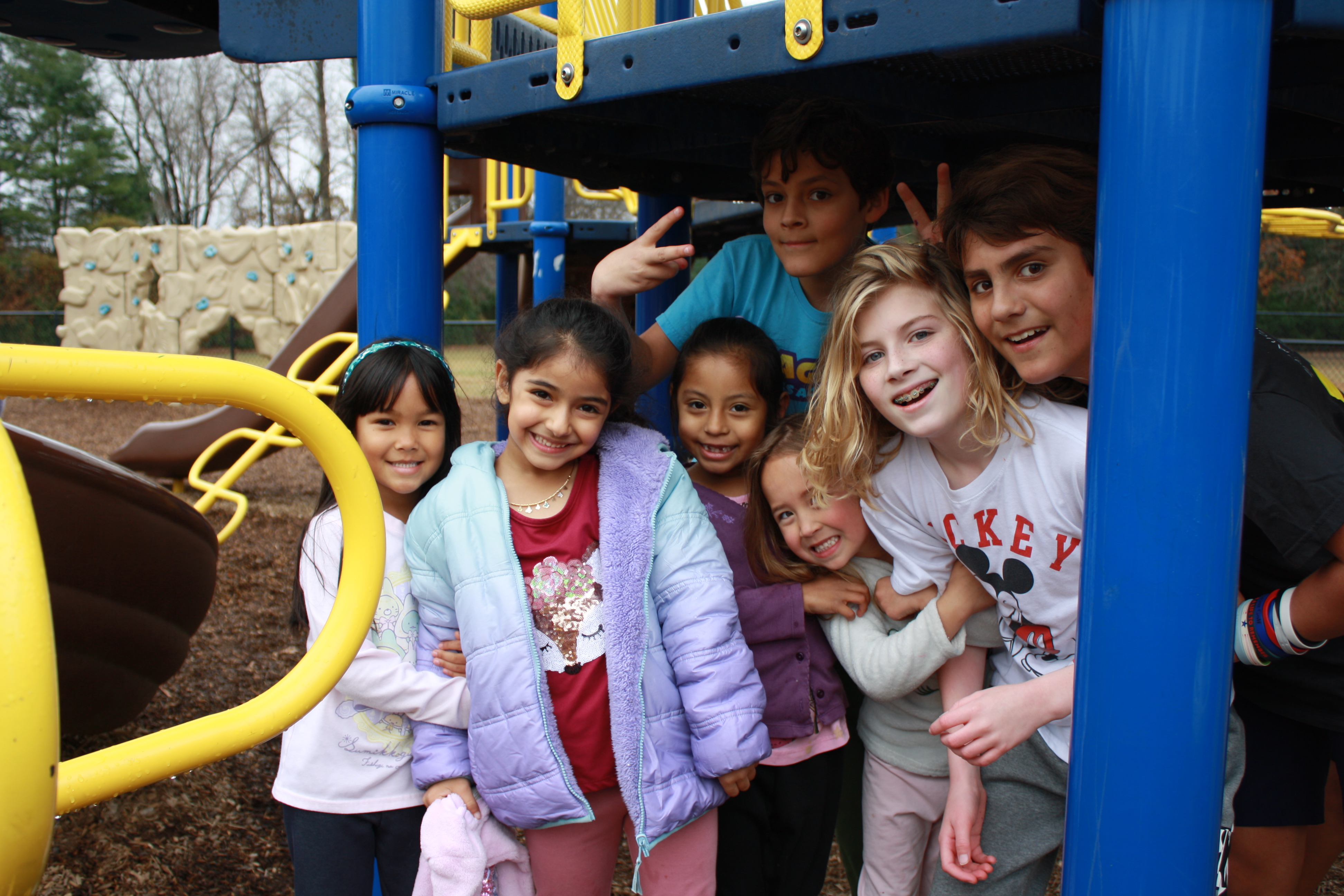 a group of students grades 2-6 pose together on the playground